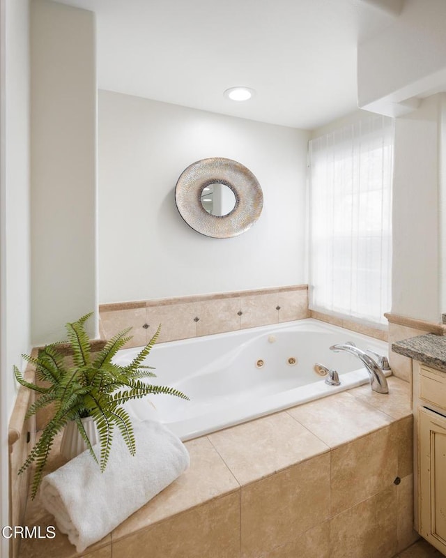 bathroom with vanity and tiled bath