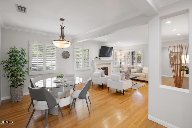 dining room with crown molding, beamed ceiling, and light wood-type flooring