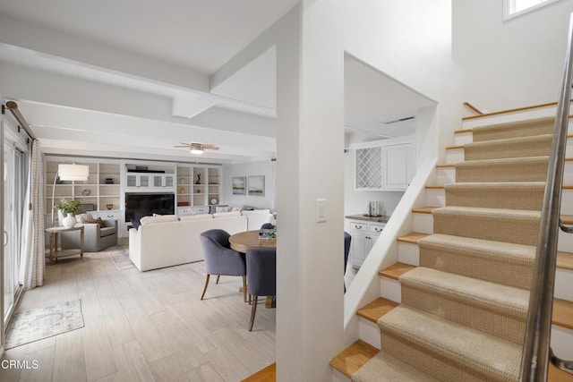 staircase featuring beamed ceiling, hardwood / wood-style flooring, and ceiling fan