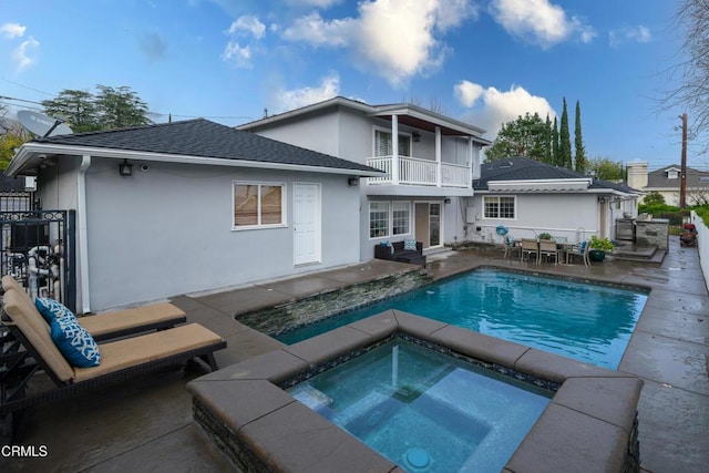 back of house featuring a pool with hot tub, a patio, and a balcony