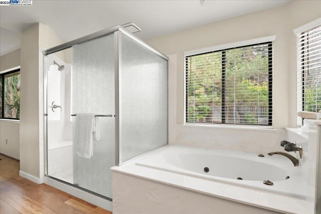 bathroom featuring independent shower and bath, wood-type flooring, and a healthy amount of sunlight