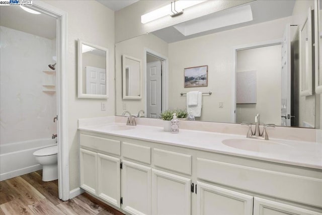 full bathroom featuring hardwood / wood-style flooring, shower / tub combination, vanity, and toilet