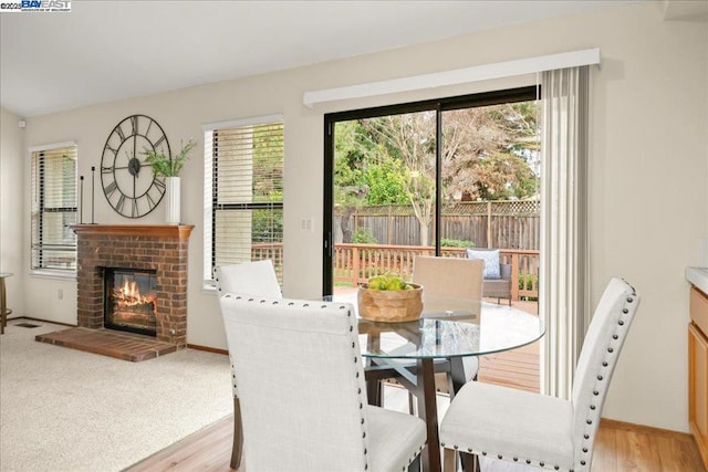 dining space with a brick fireplace and light hardwood / wood-style floors