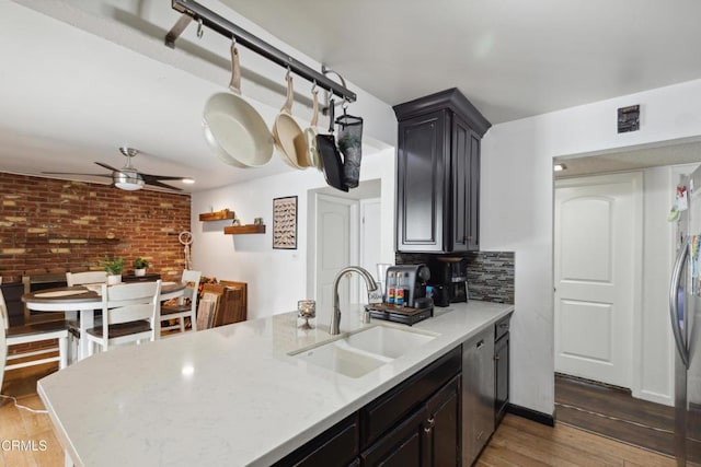 kitchen with sink, light wood-type flooring, stainless steel dishwasher, ceiling fan, and backsplash