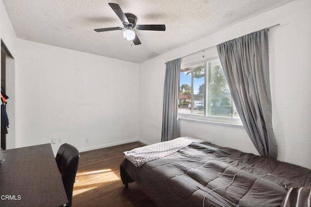 bedroom featuring ceiling fan, dark wood-type flooring, and a textured ceiling