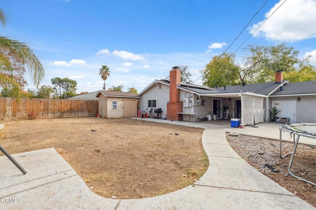 rear view of property featuring a patio area, a shed, and solar panels