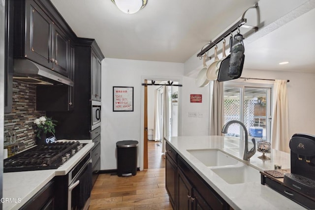 kitchen featuring sink, appliances with stainless steel finishes, light hardwood / wood-style floors, decorative backsplash, and a barn door