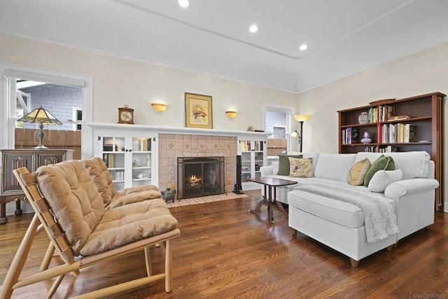 living room with a tile fireplace and dark hardwood / wood-style flooring