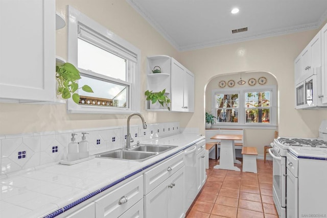 kitchen featuring sink, crown molding, white appliances, tile counters, and white cabinets