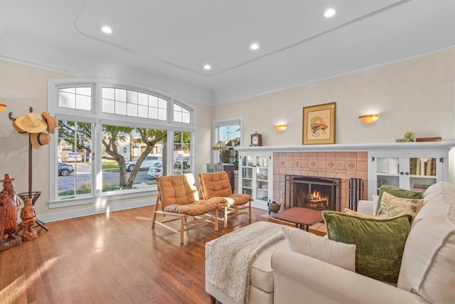 living room with ornamental molding, a tiled fireplace, and hardwood / wood-style floors