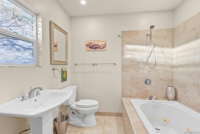 bathroom featuring a relaxing tiled tub, sink, tile patterned flooring, and toilet