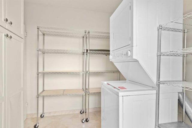 laundry room with cabinets and stacked washer / dryer