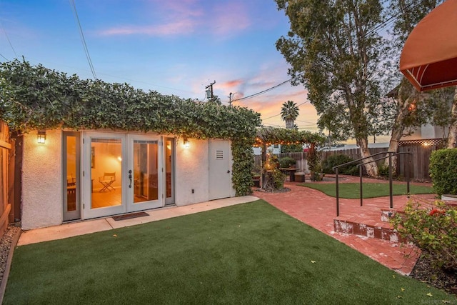 yard at dusk featuring french doors and a patio area