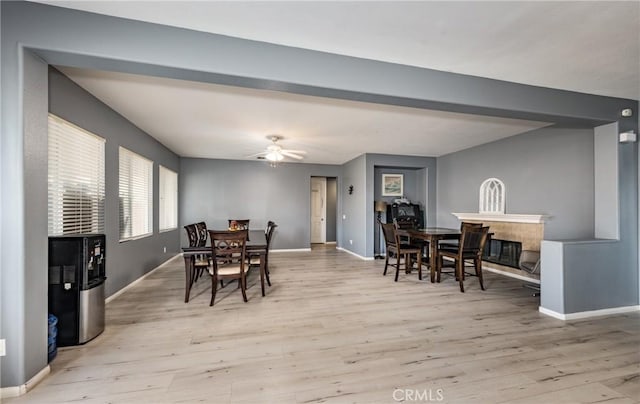 dining space with a glass covered fireplace, light wood-style flooring, and baseboards