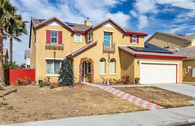 mediterranean / spanish home with a chimney, stucco siding, solar panels, concrete driveway, and a garage