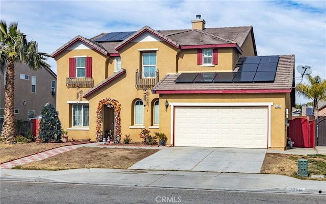 view of front of property featuring a chimney, solar panels, stucco siding, driveway, and a tiled roof