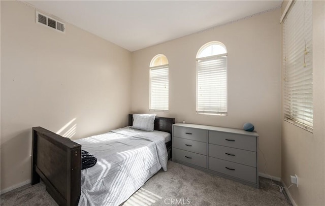 bedroom with baseboards, visible vents, and light colored carpet