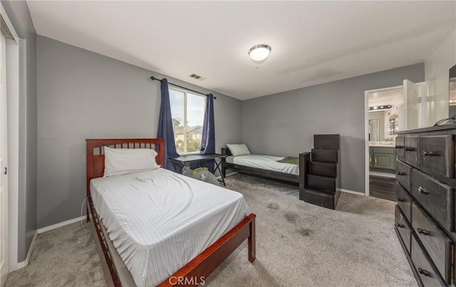 carpeted bedroom with ensuite bath, baseboards, and visible vents