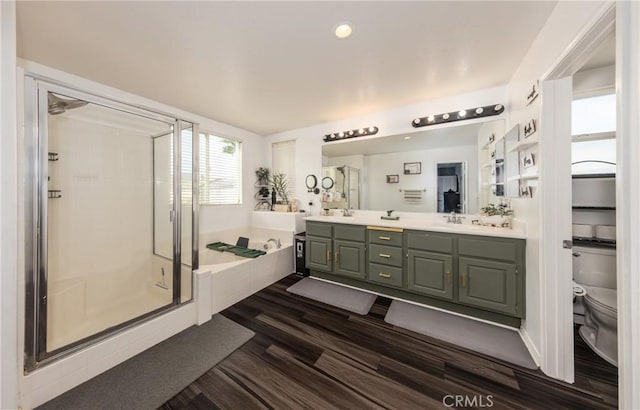 full bathroom featuring a garden tub, toilet, wood finished floors, a shower stall, and double vanity