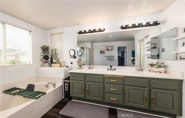 bathroom with hardwood / wood-style flooring, vanity, and tiled tub