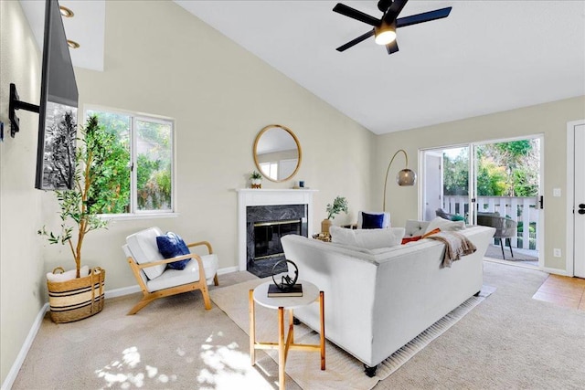 carpeted living room with ceiling fan, high vaulted ceiling, a premium fireplace, and a healthy amount of sunlight