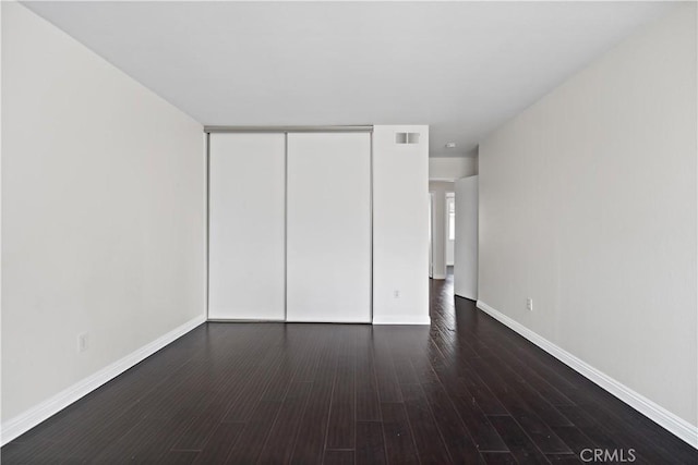 unfurnished bedroom featuring dark hardwood / wood-style flooring and a closet