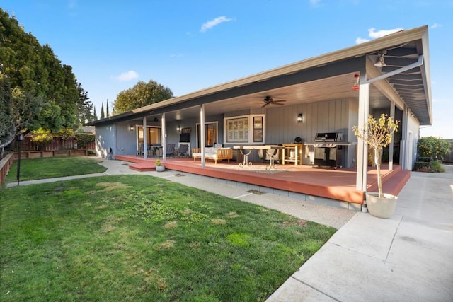 rear view of house with a wooden deck, ceiling fan, and a yard