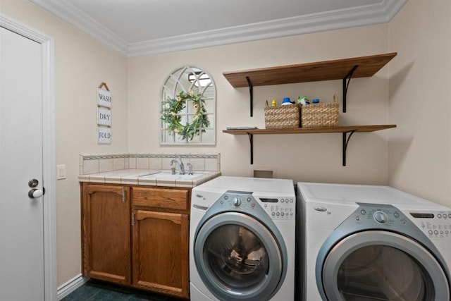 washroom featuring sink, ornamental molding, washing machine and dryer, and cabinets