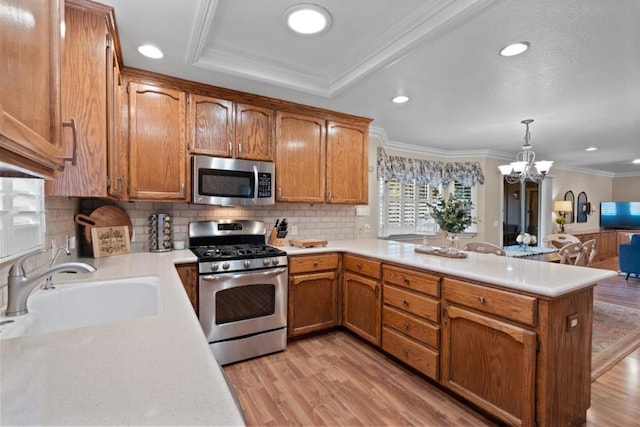 kitchen with sink, crown molding, stainless steel appliances, decorative light fixtures, and kitchen peninsula