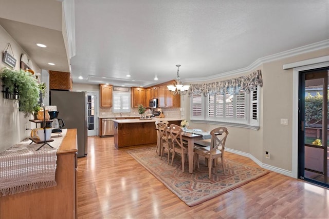 dining area with ornamental molding, a notable chandelier, and light hardwood / wood-style flooring