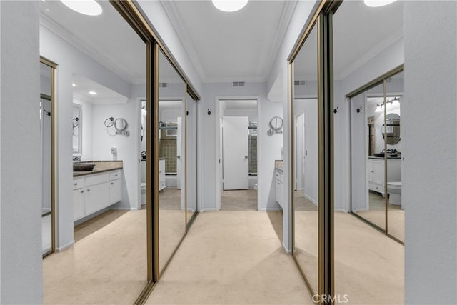 hallway with crown molding, sink, and light carpet