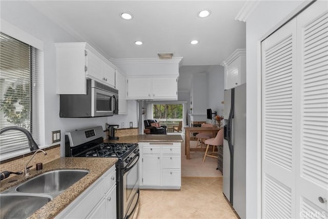 kitchen with dark stone countertops, appliances with stainless steel finishes, sink, and white cabinets