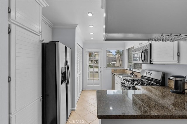 kitchen featuring sink, dark stone countertops, light tile patterned floors, appliances with stainless steel finishes, and white cabinets