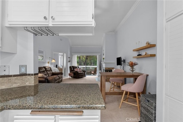 kitchen with light colored carpet, ornamental molding, and stone counters