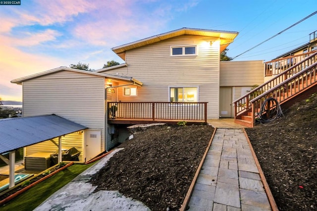 back house at dusk with a wooden deck and central AC