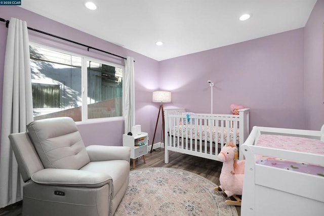 bedroom featuring dark hardwood / wood-style flooring and a crib