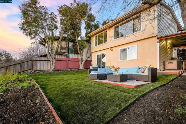 back house at dusk with an outdoor hangout area, a patio area, and a lawn