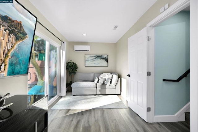 living area with hardwood / wood-style floors and an AC wall unit