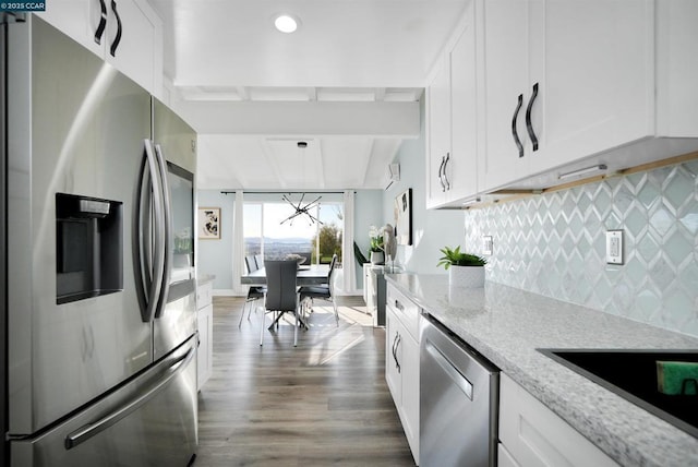 kitchen featuring tasteful backsplash, light stone countertops, stainless steel appliances, and white cabinets