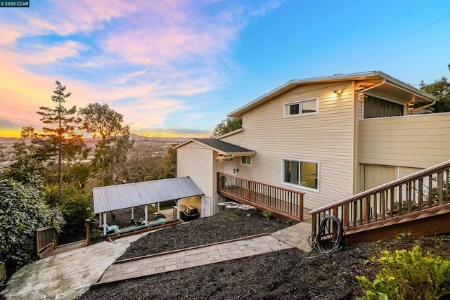 back house at dusk with a gazebo, a wooden deck, and a patio