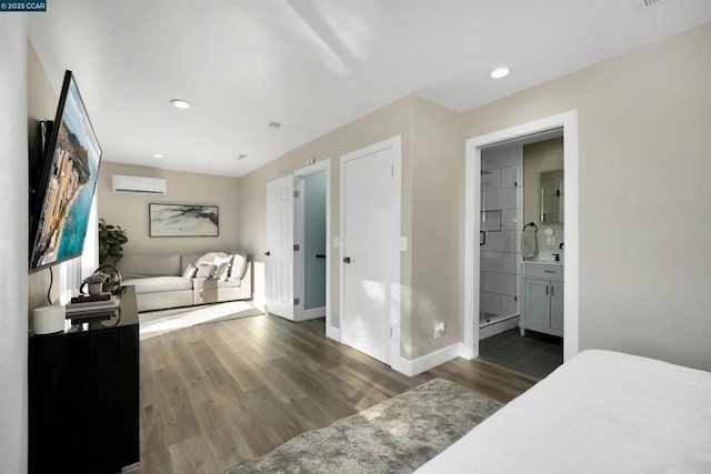 bedroom featuring ensuite bathroom, dark hardwood / wood-style floors, and an AC wall unit