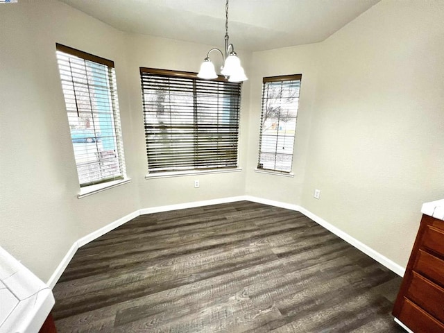 unfurnished dining area with dark hardwood / wood-style flooring and an inviting chandelier