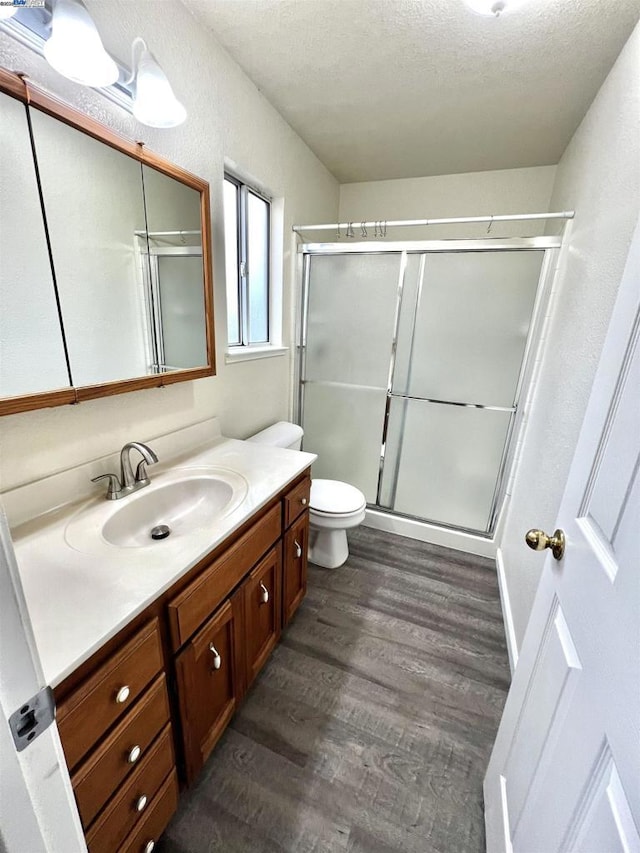 bathroom with hardwood / wood-style flooring, vanity, and a shower with door