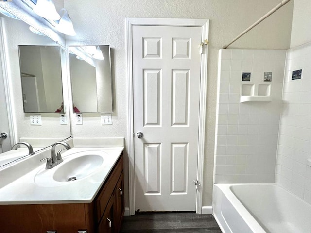 bathroom featuring hardwood / wood-style flooring, vanity, and  shower combination