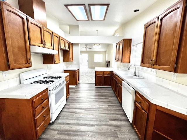 kitchen with dark hardwood / wood-style floors, white appliances, tile countertops, and sink