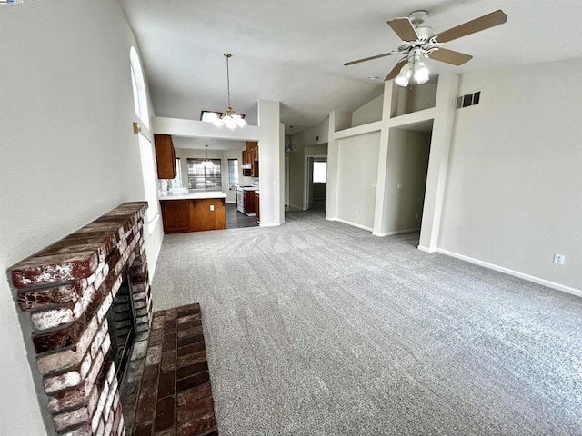 unfurnished living room with high vaulted ceiling, ceiling fan with notable chandelier, and carpet