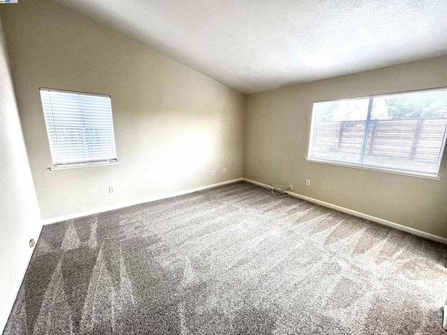 carpeted spare room with vaulted ceiling