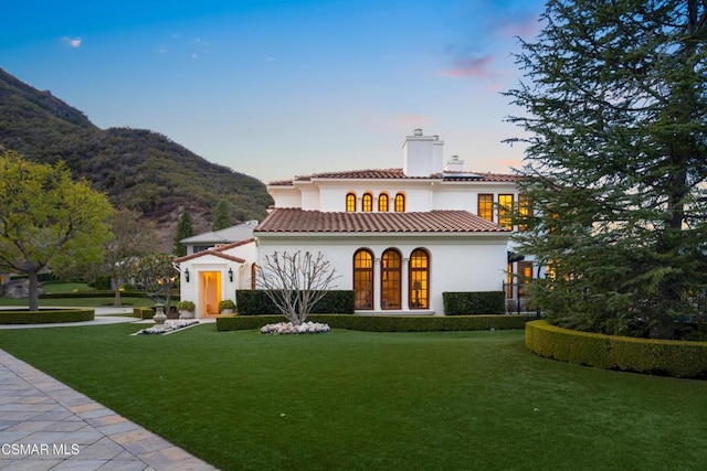 back house at dusk featuring a mountain view, a yard, and french doors