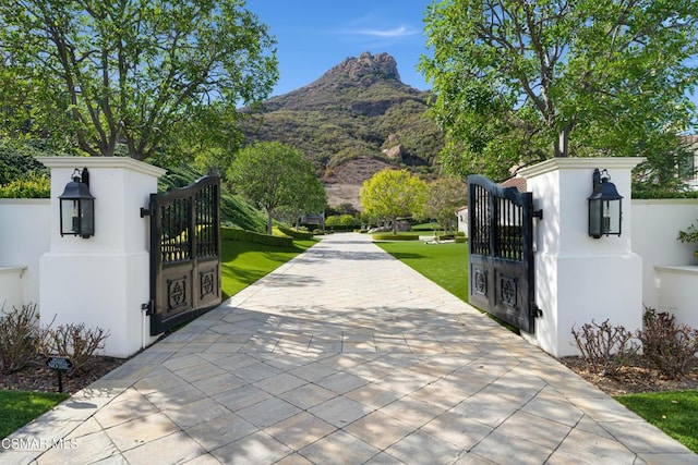 view of gate featuring a mountain view and a lawn