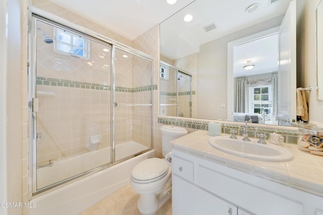 full bathroom with vanity, toilet, combined bath / shower with glass door, and a wealth of natural light